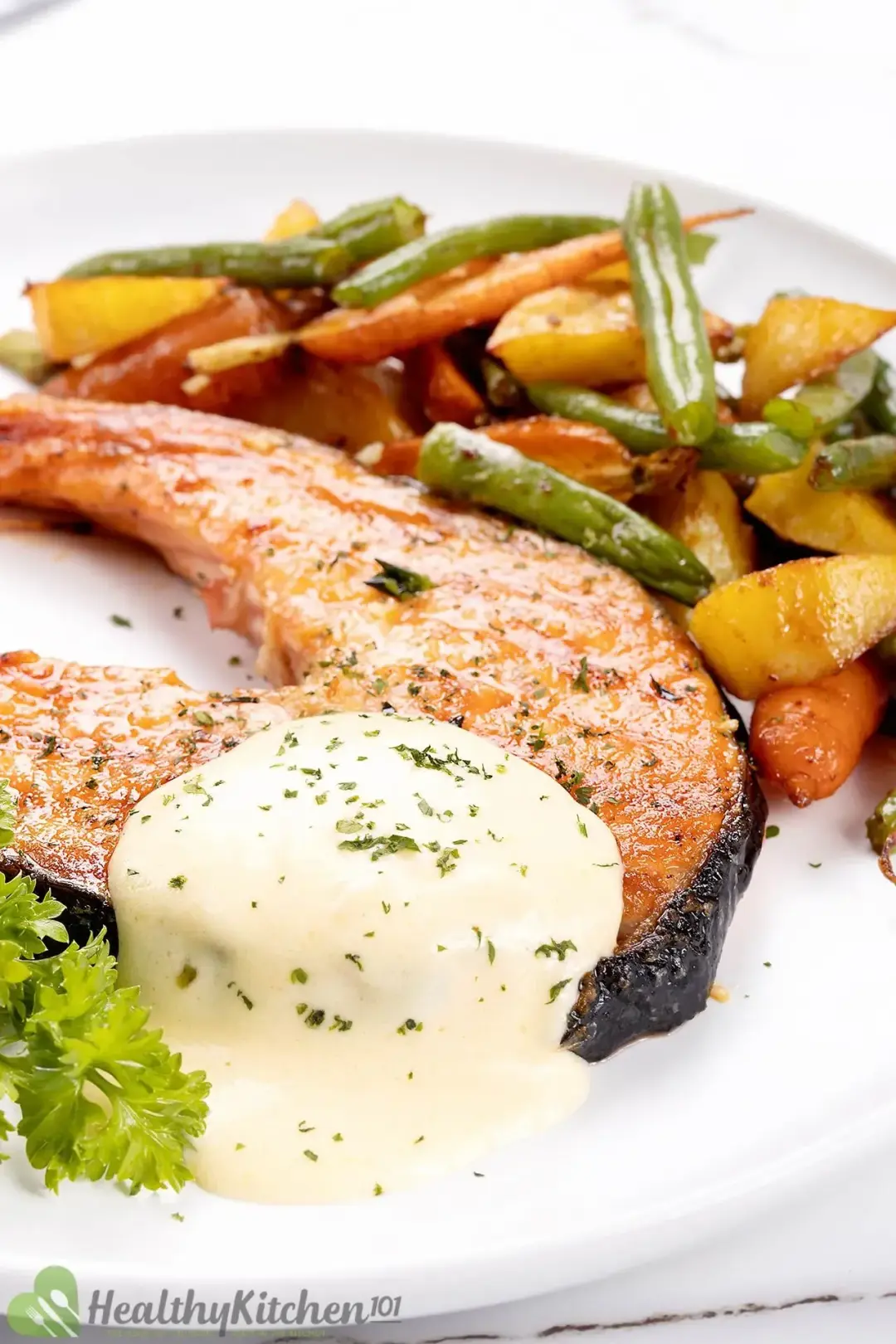 A glossy salmon steak dolloped with cream and served with roasted baby vegetables