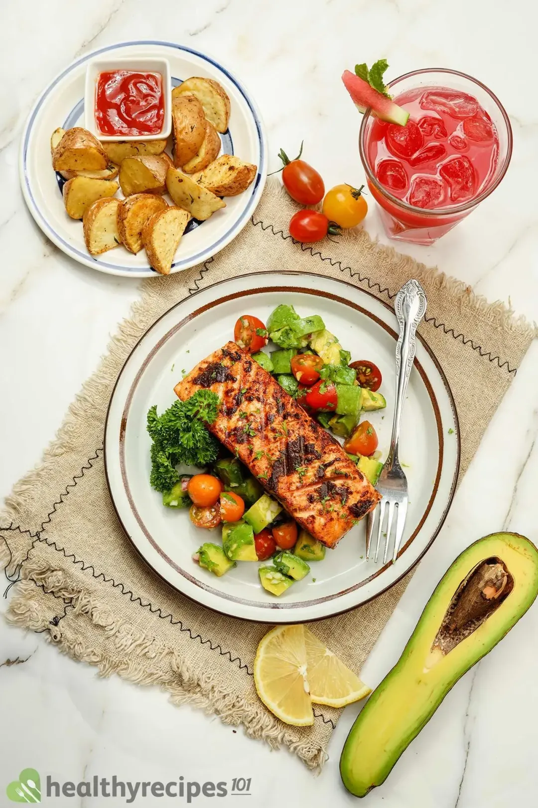 A plate of salmon avocado alongside a plate of air fryer potato wedges with sauce and a glass of watermelon juice