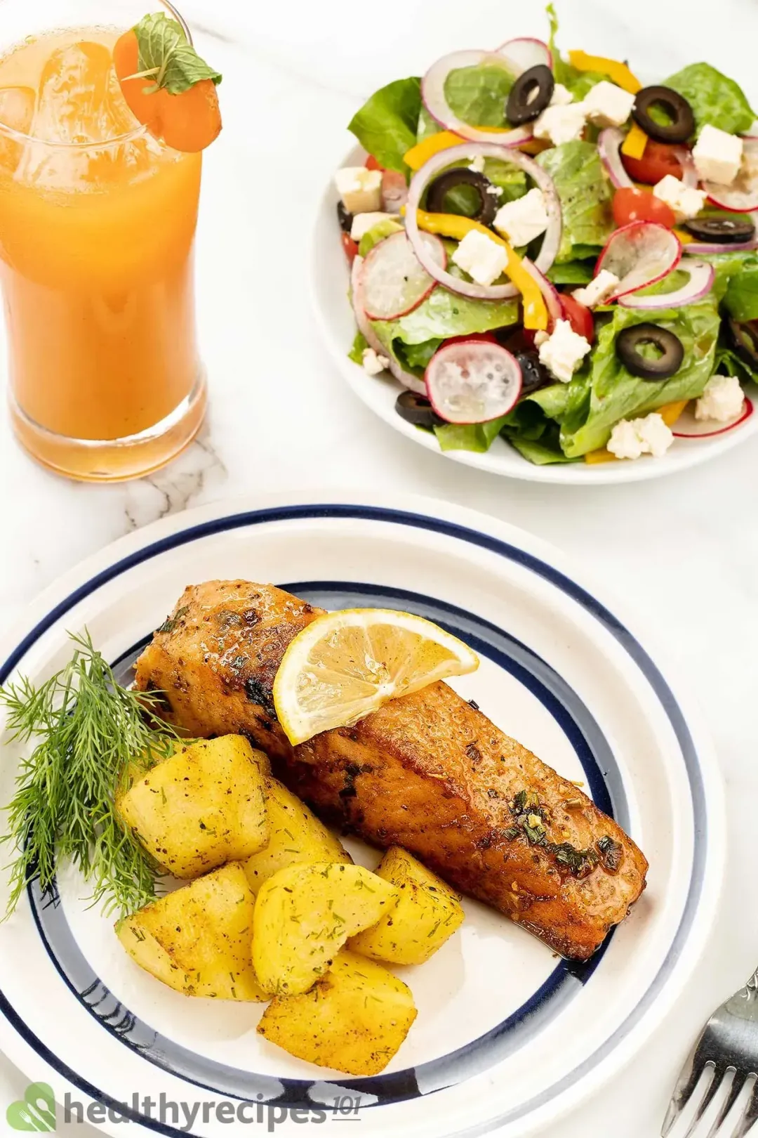 A white Chinese plate with a golden salmon filet topped with a lemon slice, potato wedges tossed with dill, and a dill sprig