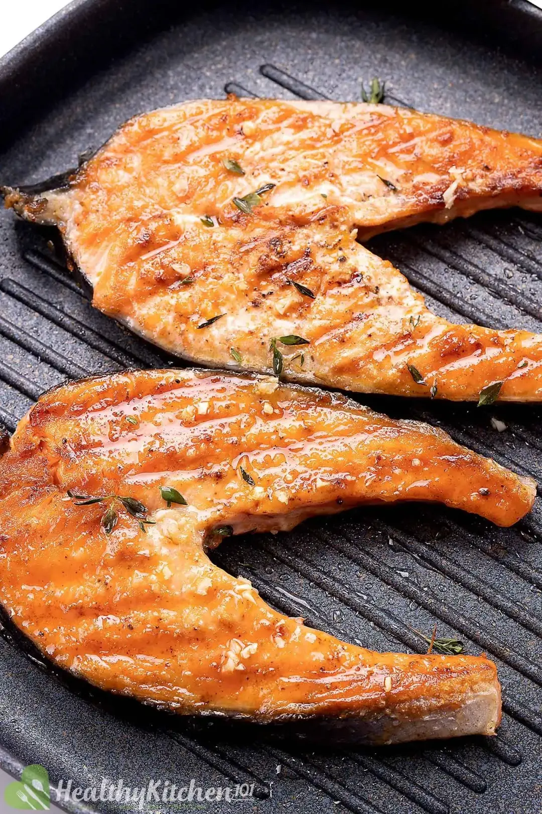 Two golden and glossy pieces of salmnon steak in a grill pan
