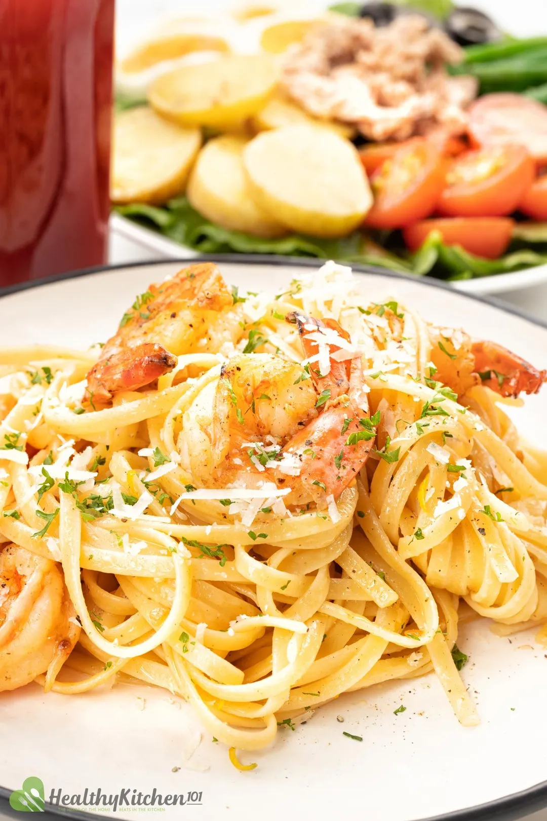 A plate of shrimp fettuccine next to a bloody mary cocktail and a plate of egg, potato salad