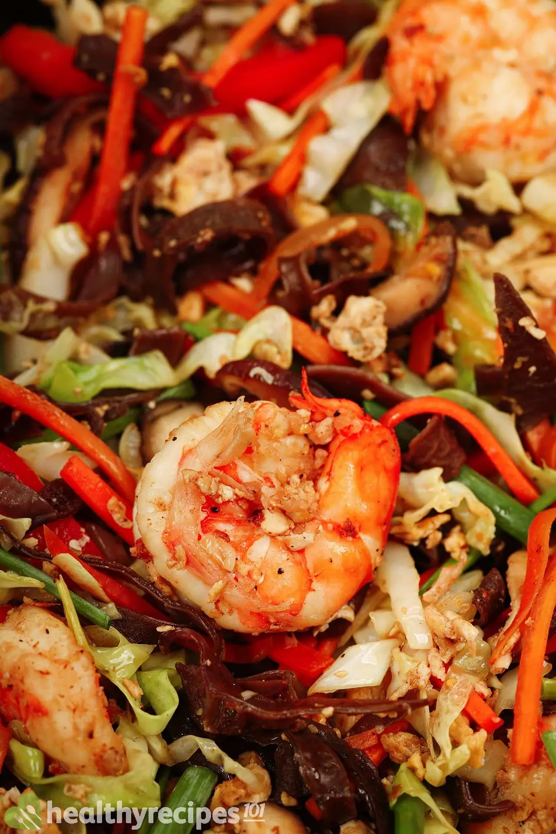 A close-up shot of shrimp, julienned wood ear, cabbage, pepper, and carrot sauteed together