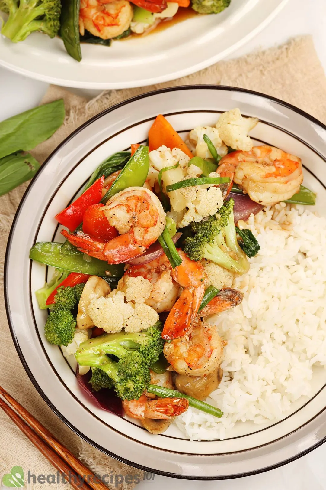 A pan full of shrimp chop suey with halved mushrooms and raw snow peas as decorations.