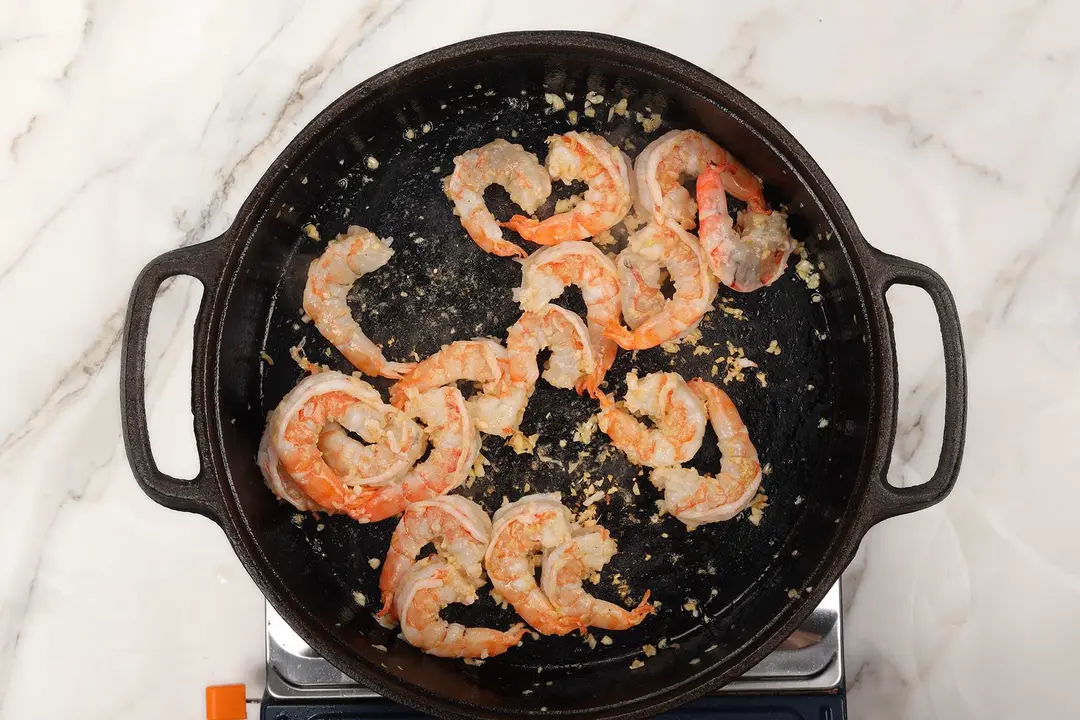 Peeled shrimp seared inside a cast-iron skillet with minced garlic