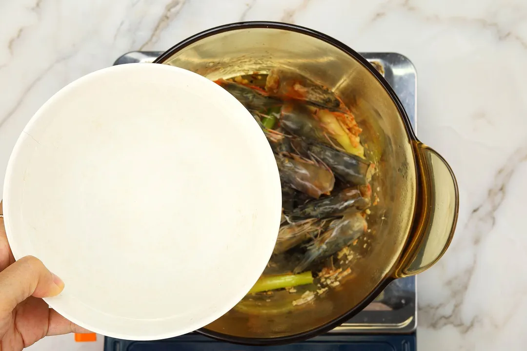 a bowl of water on top of a pot of shrimp head