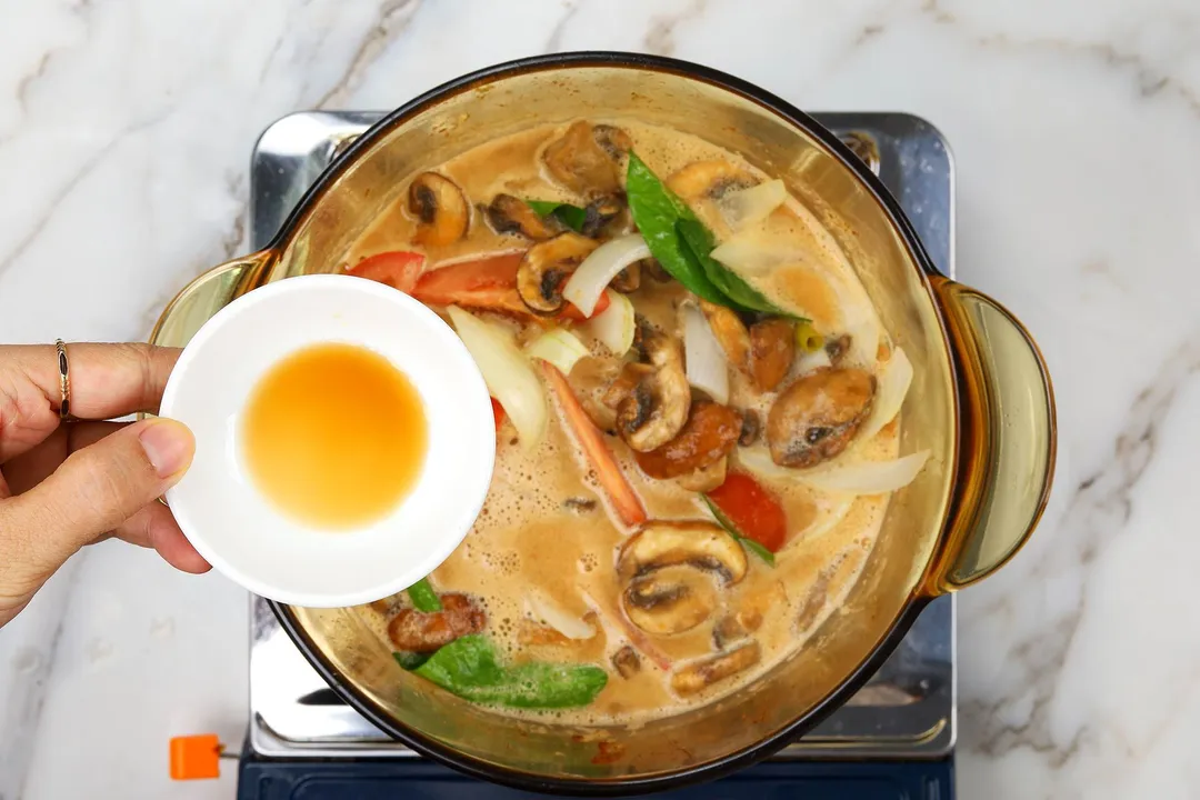 a small bowl of fish sauce on top of a pot of tom yum soup