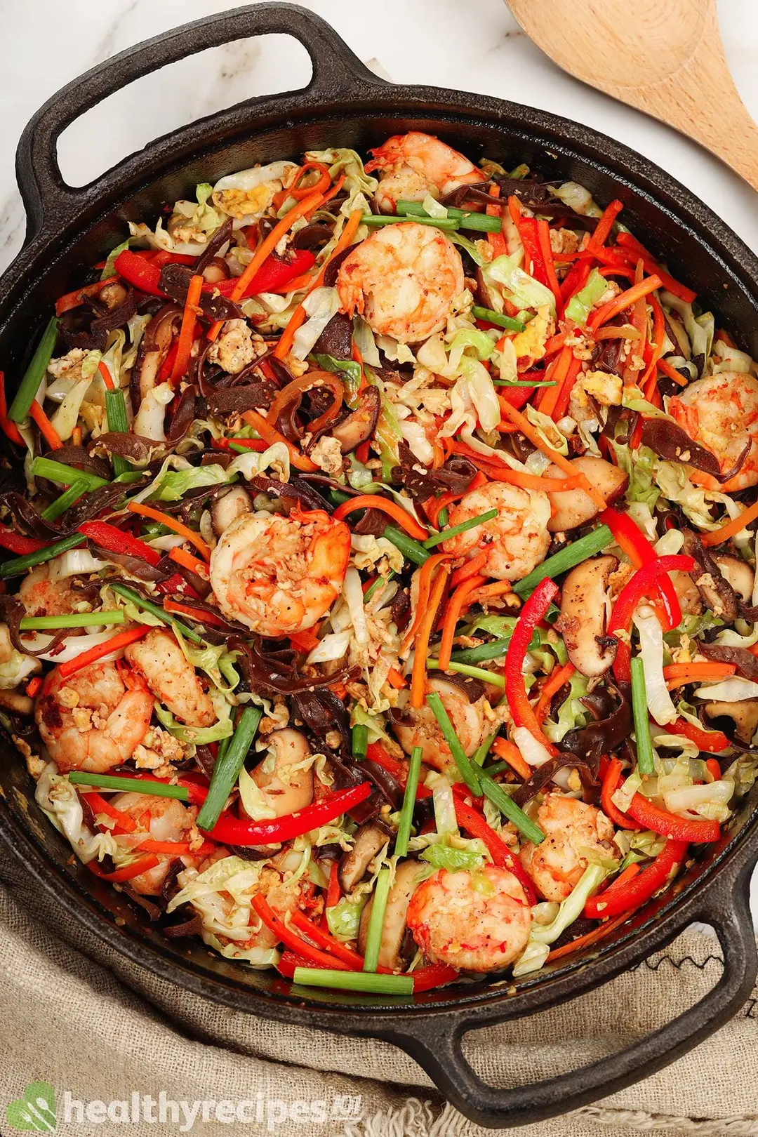 A colorful saute of shrimp, wood ear, carrot, and pepper in a black cast-iron skillet