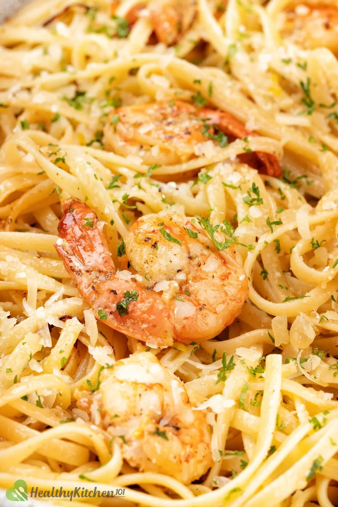 A closeup shot of shrimp fettuccine with minced parsley and shaved parmesan on top