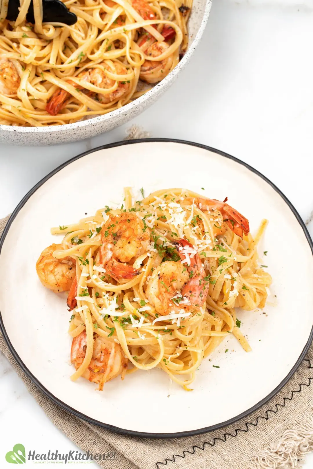 Some shrimp fettuccine in a plate, next to a pan of shrimp pasta