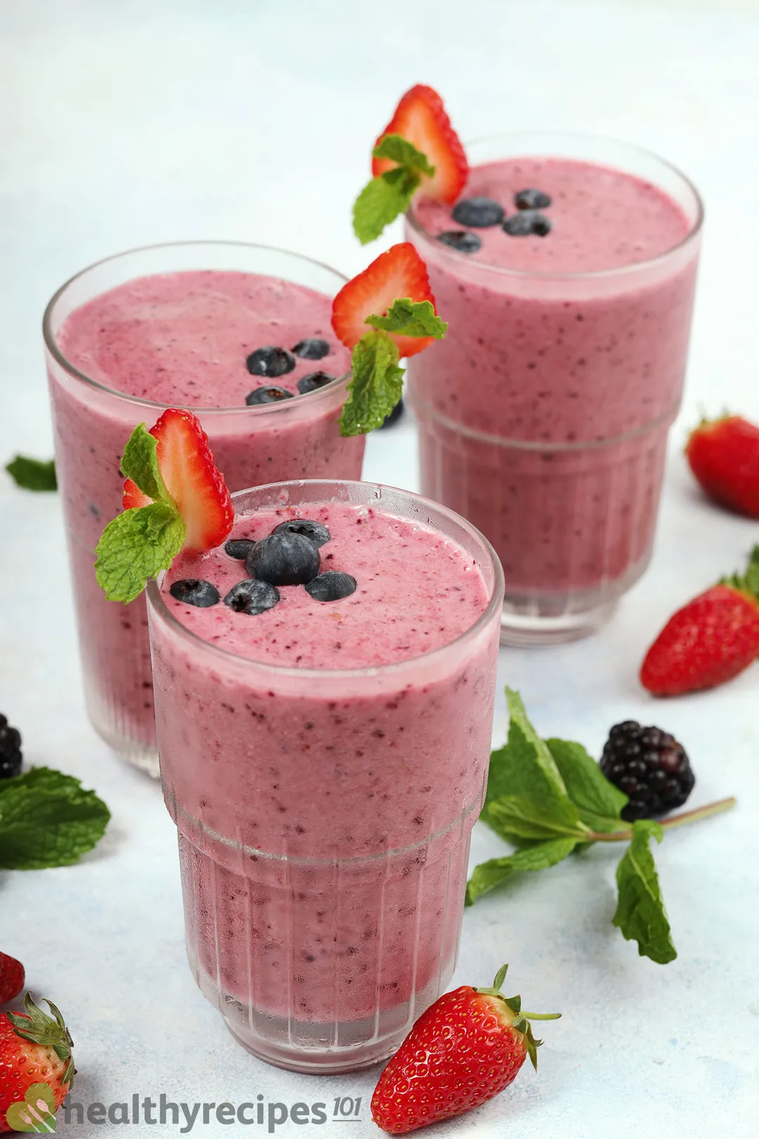 three pink glasses of berry smoothie