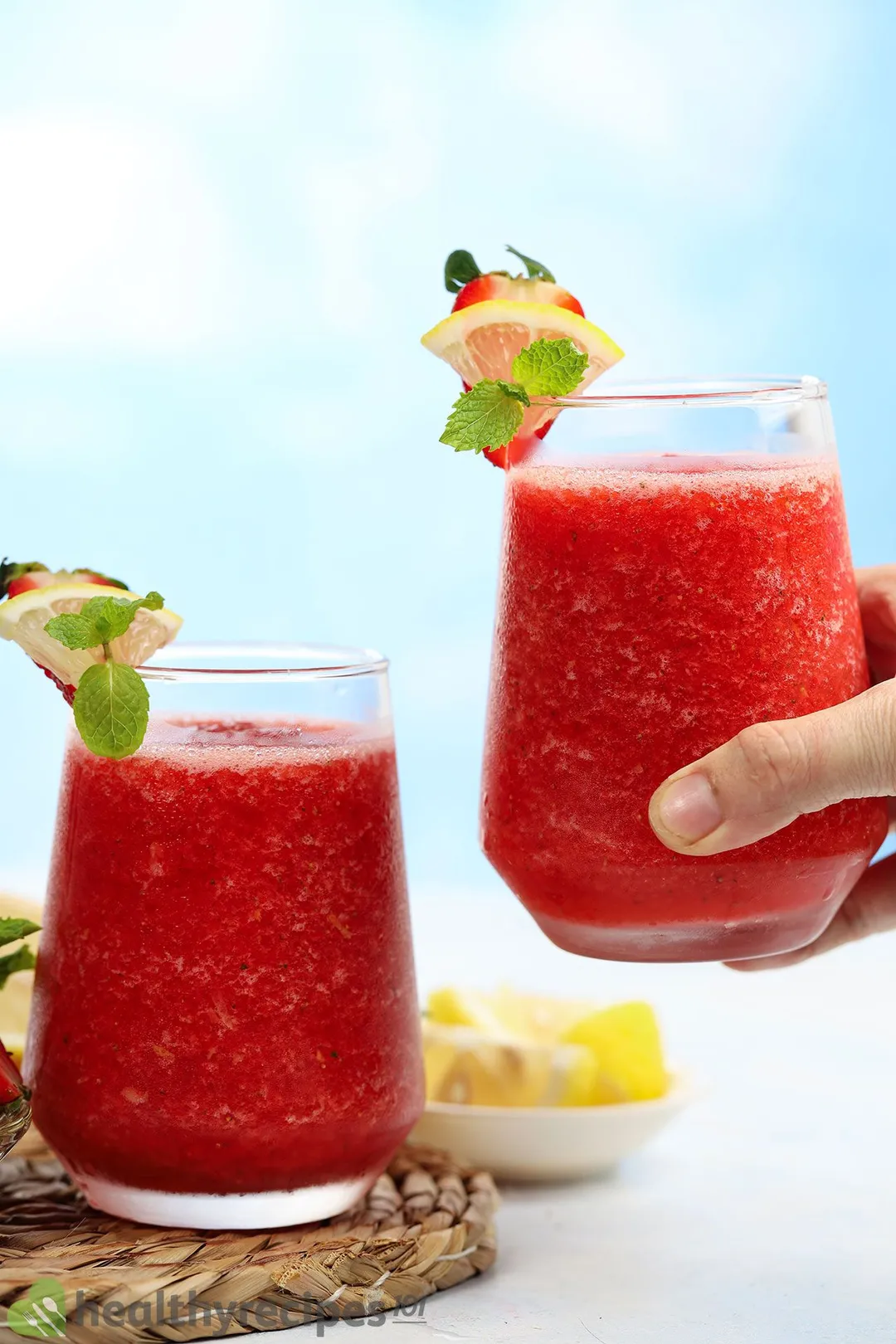 two glasses of strawberry lemonade smoothie, hand holds one