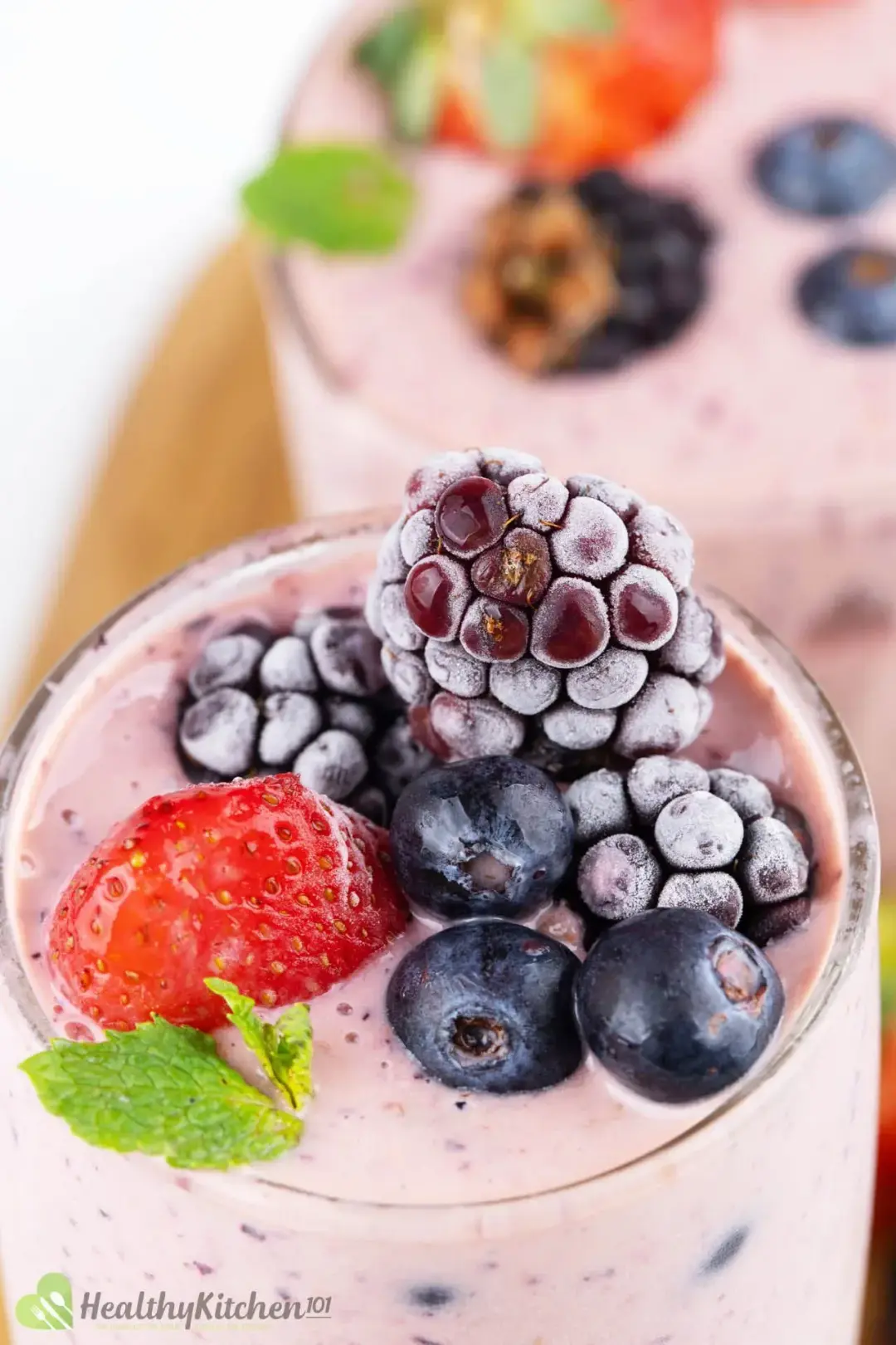 A close-up shot of two smoothie glasses, both filled with berries on top