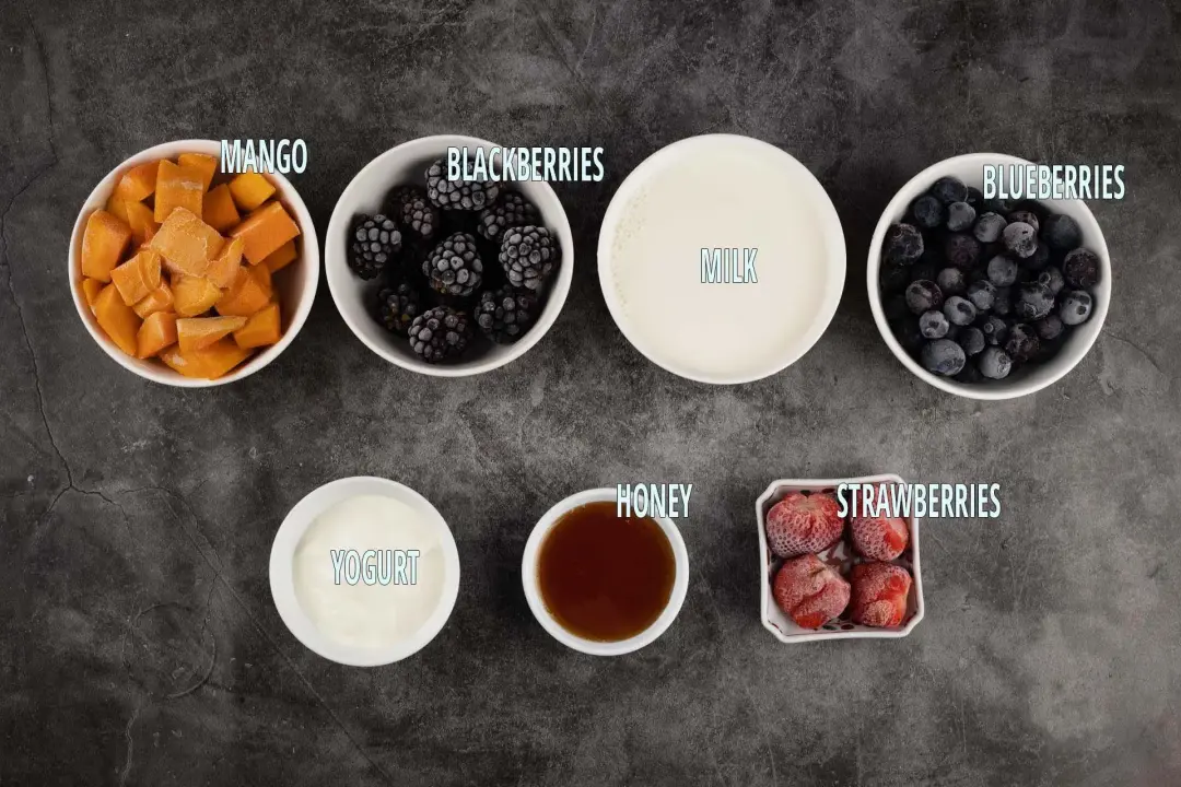 Ingredients: Frozen mango cubes, frozen blackberries, milk, frozen blueberries, yogurt, honey, and frozen strawberries kept in separate bowls