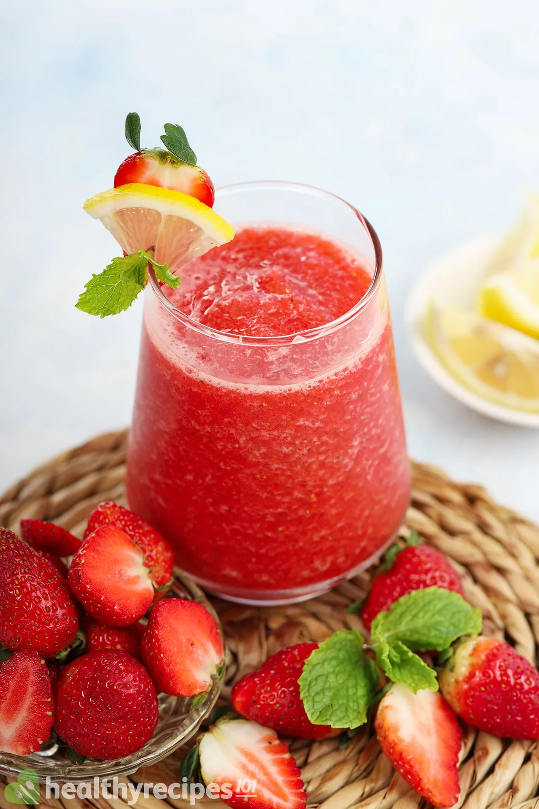 a glass of strawberry smoothie surrounded by strawbberries