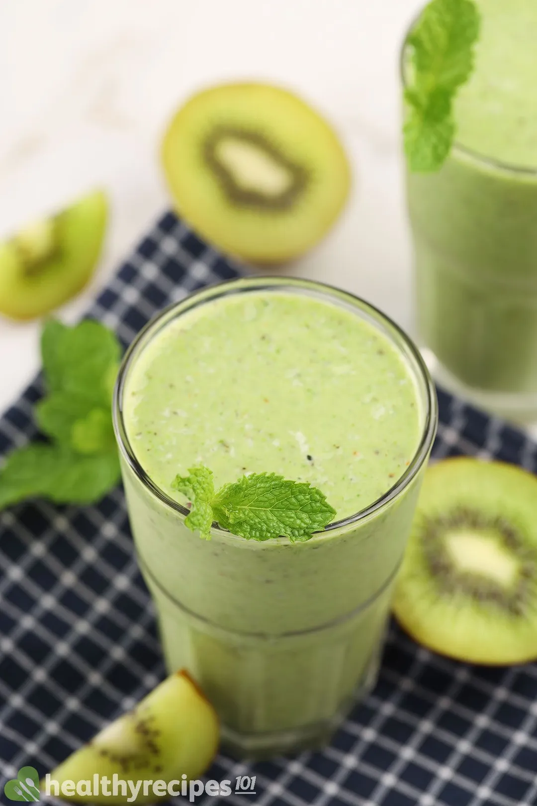 A high-angle shot of kiwi smoothie glasses surrounded by sliced green kiwi.