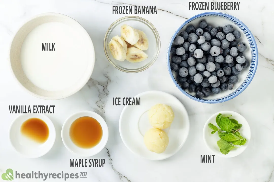 Ingredients for blueberry banana smoothie, including bowls of blueberries, sliced bananas, mint leaves, milk, ice cream, and others.