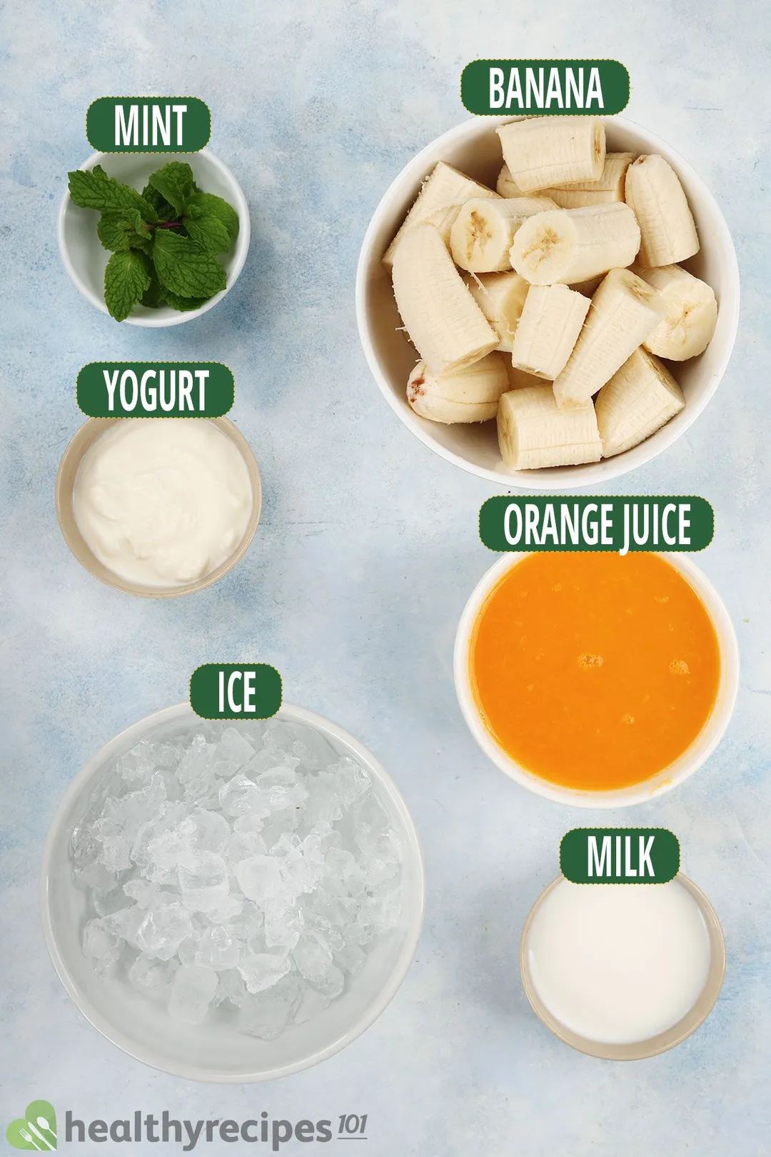 Ingredients for Orange Banana Smoothie, including peeled sliced bananas, orange juice, yogurt, ice, mint leaves, and milk.