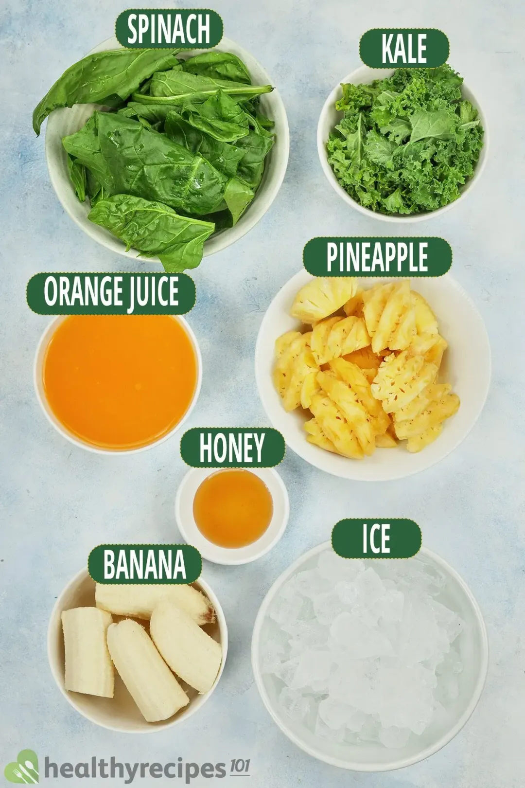 ingredients for this pineapple green smoothie: spinach leaves, kale leaves, orange juice, cubed pineapple, honey, bananas, and ice