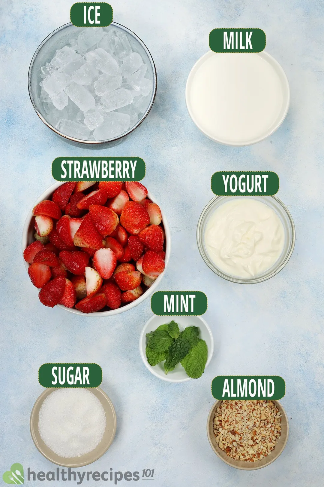 Ingredients for strawberry smoothie, including sliced strawberries, mint leaves, ice, and other smoothie essentials.