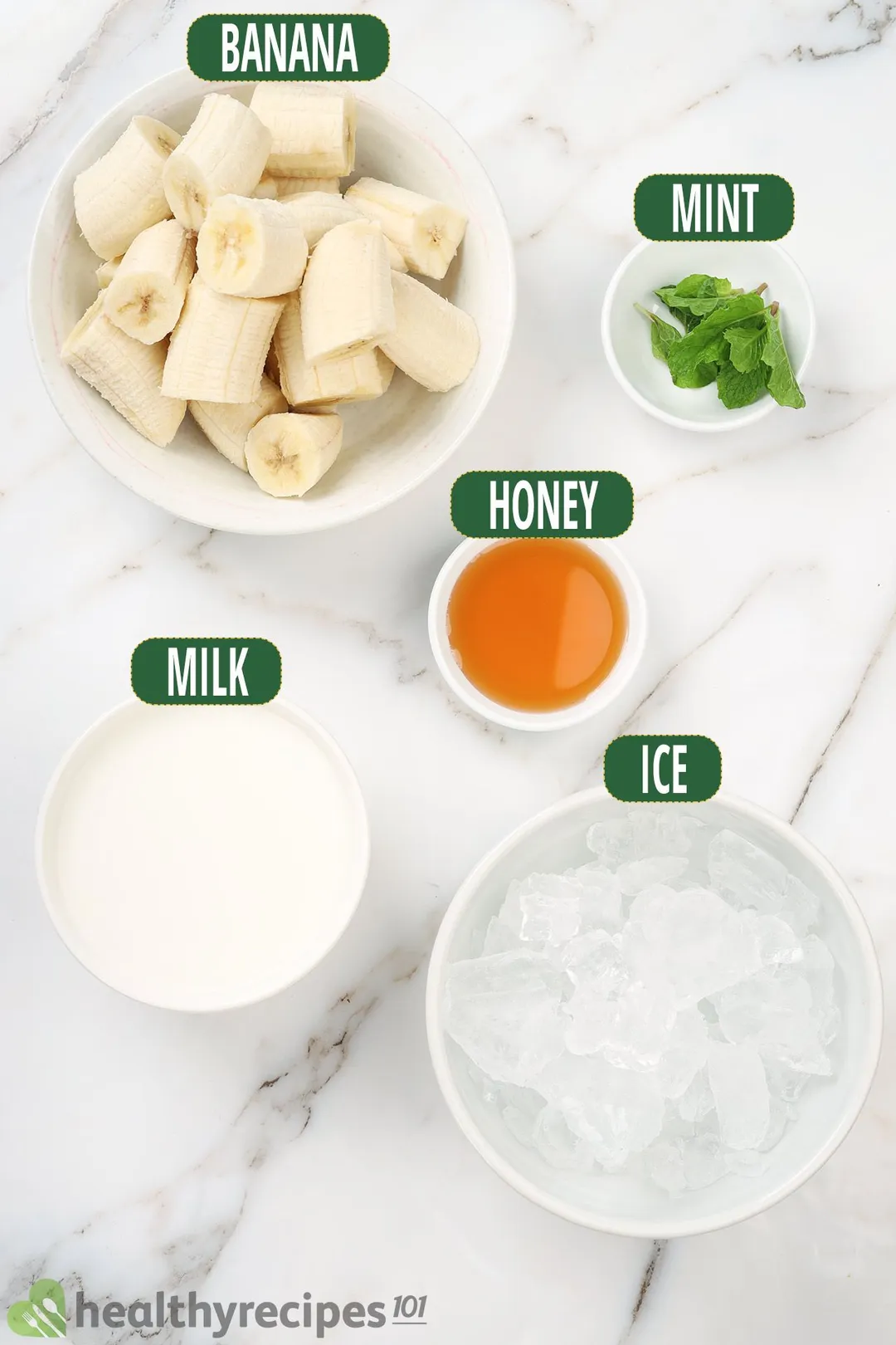 Ingredients for banana smoothie, including peeled and sliced banana, honey, mint leaves, milk, and ice. 