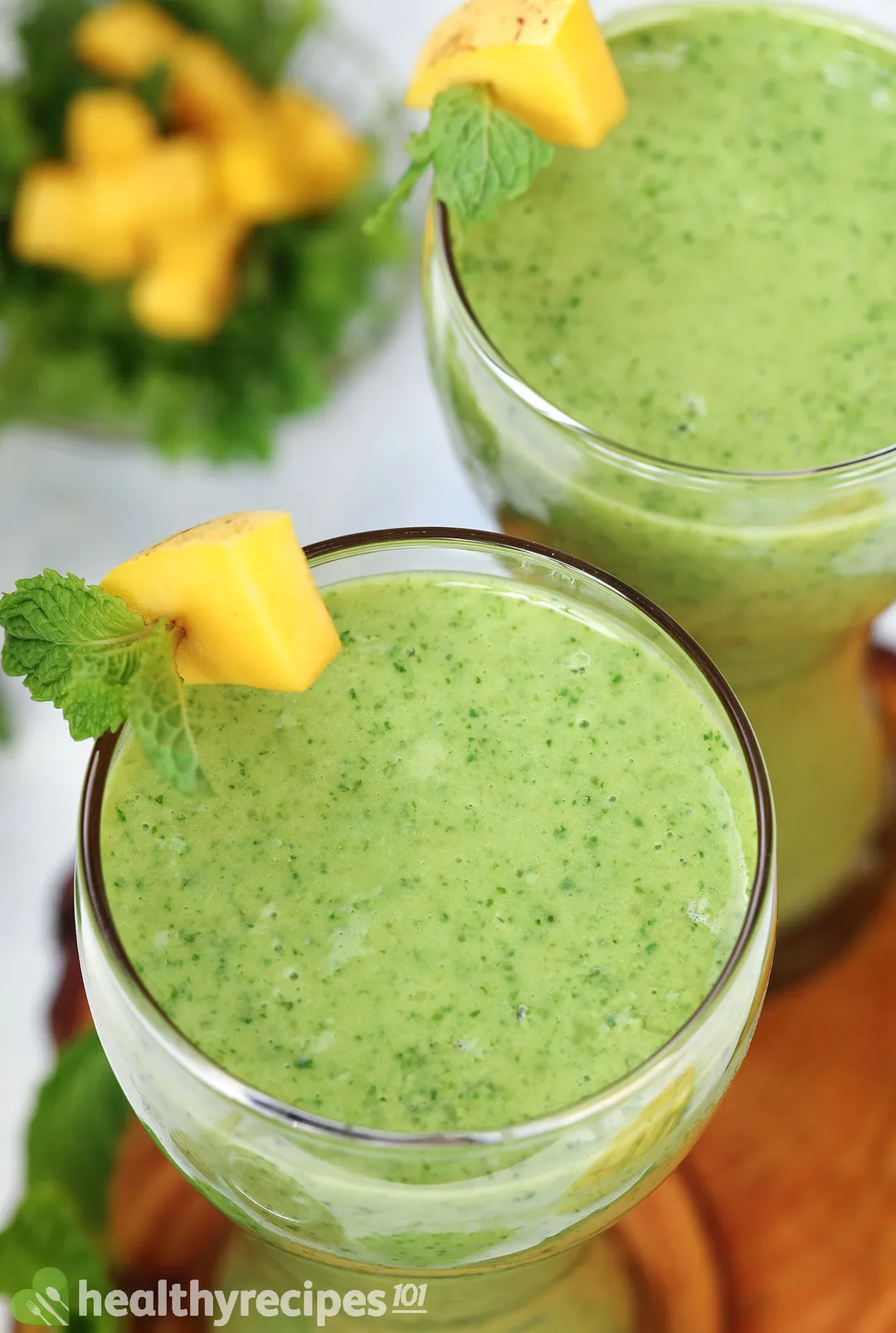 top view of two glasses of mango kale smoothie on a tray