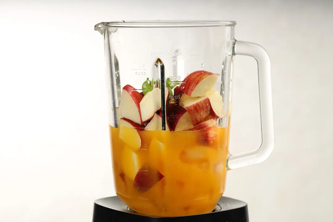 sliced apple and orange juice in a blender pitcher
