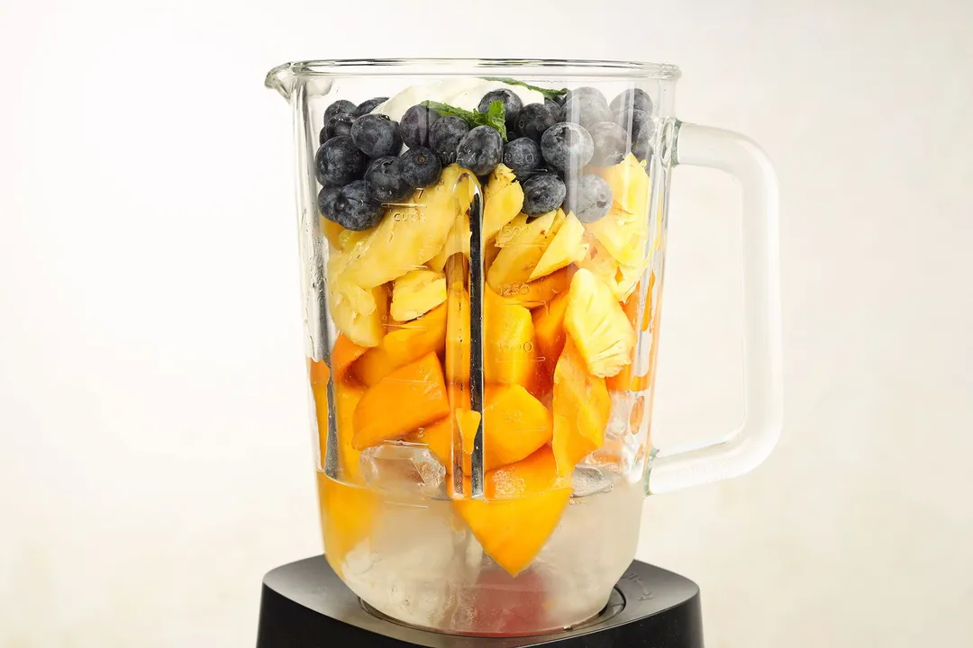 blueberry pineapple cubed, mango cubed and ice in a blender pitcher