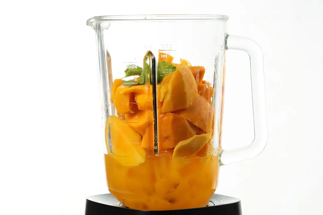 mango cubes, mint and ice in a blender pitcher