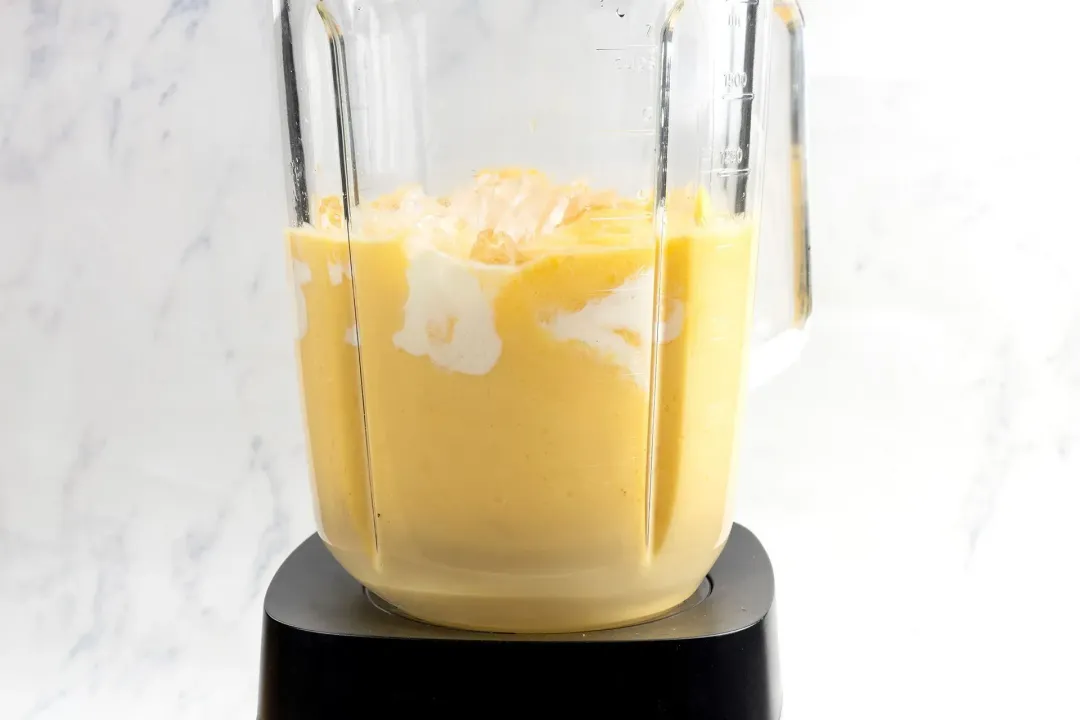 Ingredients blended in a blender, showing a uniform orange mixture with white swirls