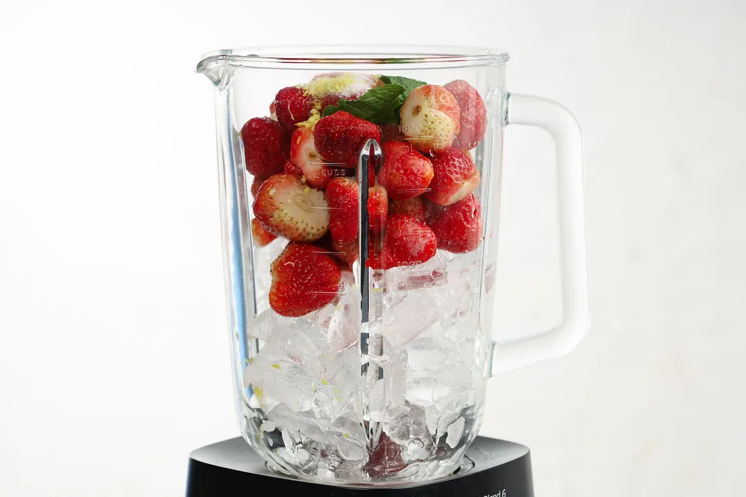 strawberries with ice and mint leaves in a blender pitcher
