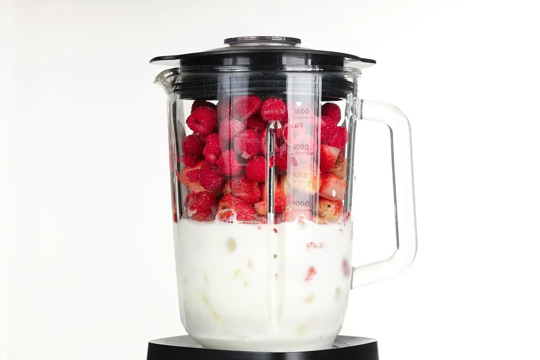 strawberry raspberry and milk in a blender pitcher