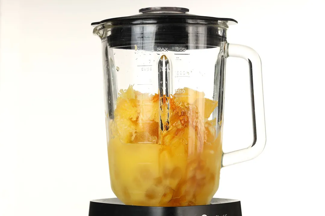 front shot of a blender pitcher with orange, orange juice, honey in it