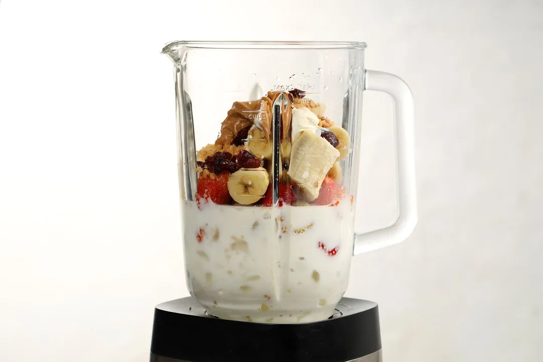 a blender pitcher of strawberry, banana cubed, chocolate, milk, almond and milk