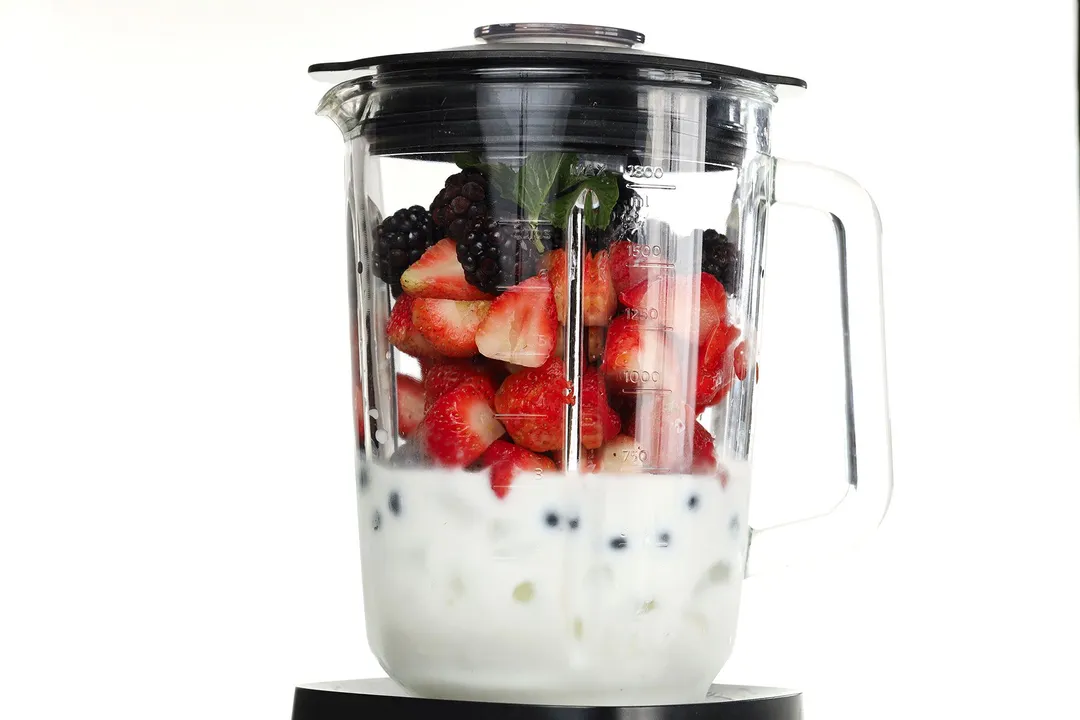 blackberries, strawberries, milk and ice in a blender pitcher