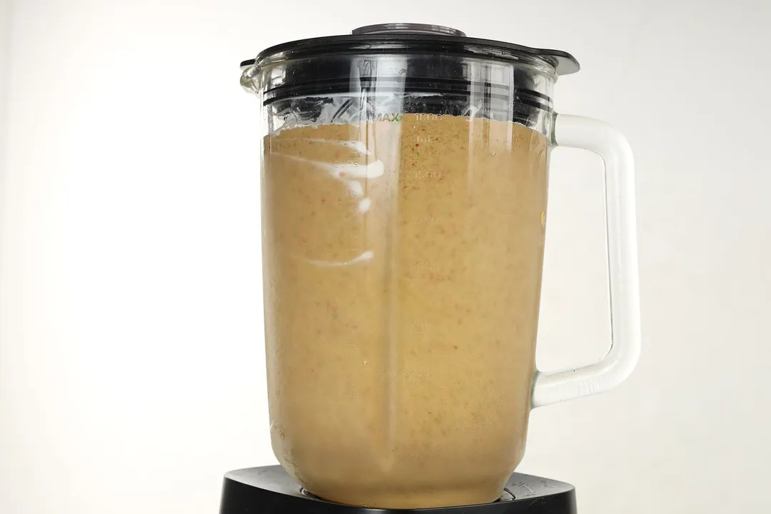 front shot of a blender pitcher with banana pineapple smoothie in it