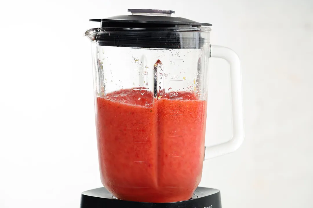 a blender pitcher of red smoothie in it