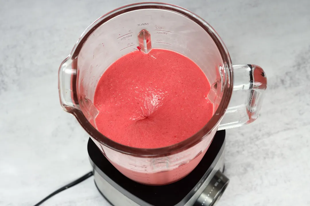 a blender pitcher of pink smoothie in it