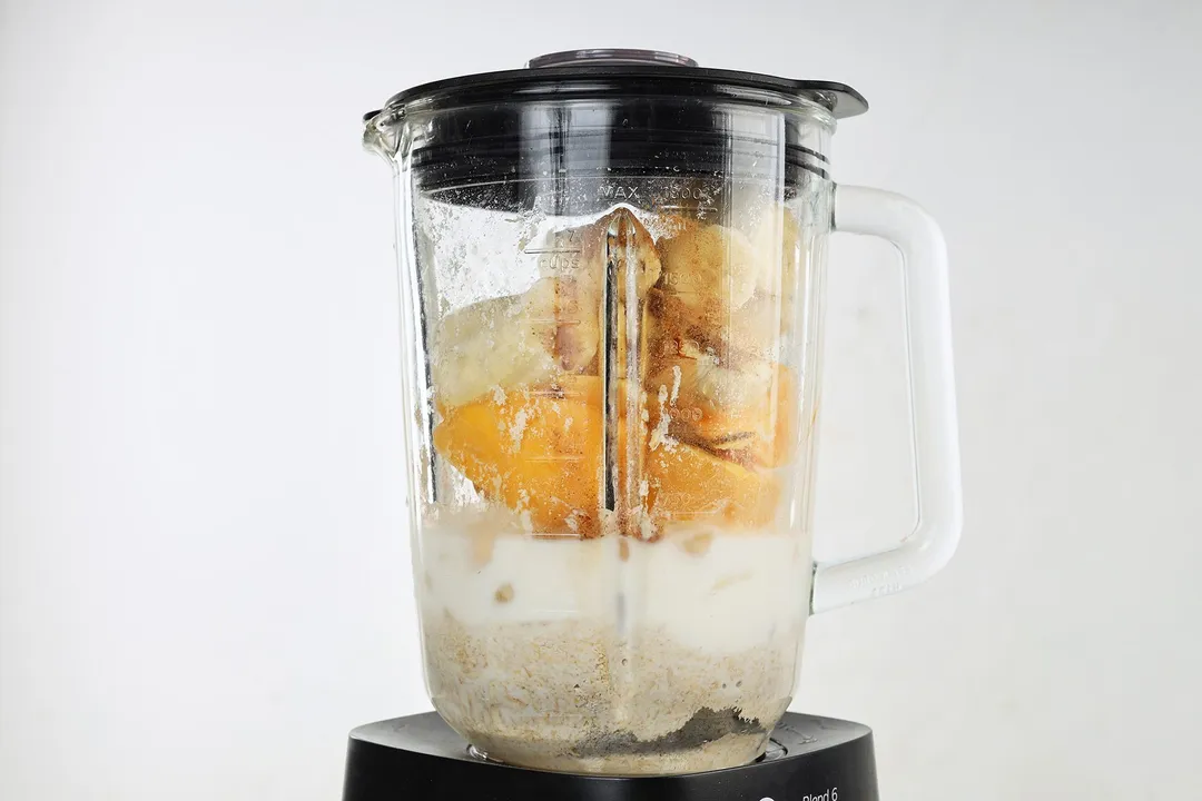 a blender of mango cubed, banana cubed, oatmeal, milk