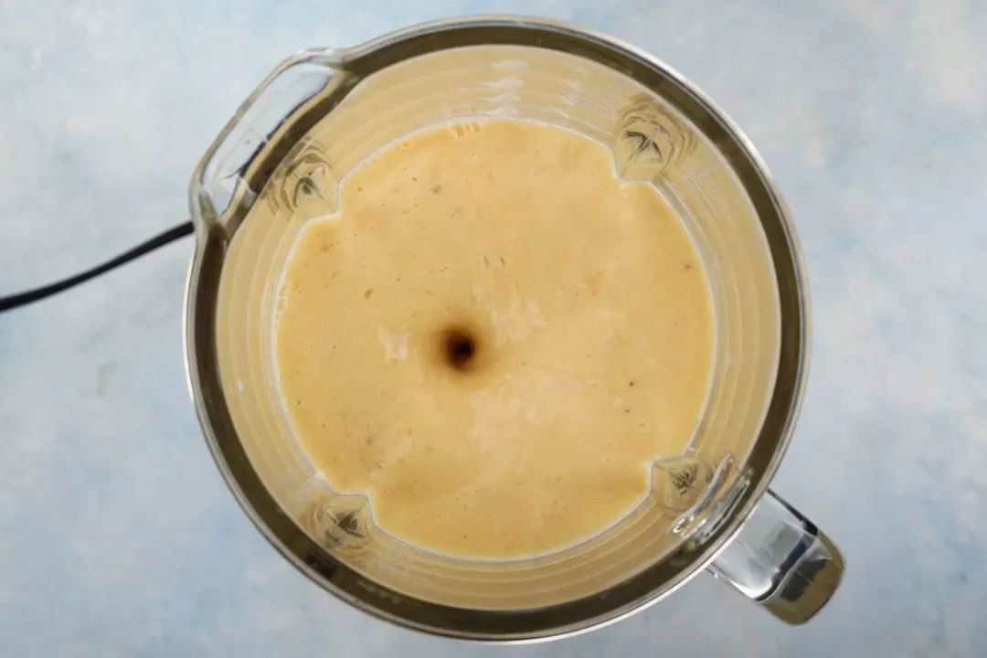 top view of a blender with orange banana smoothie in it