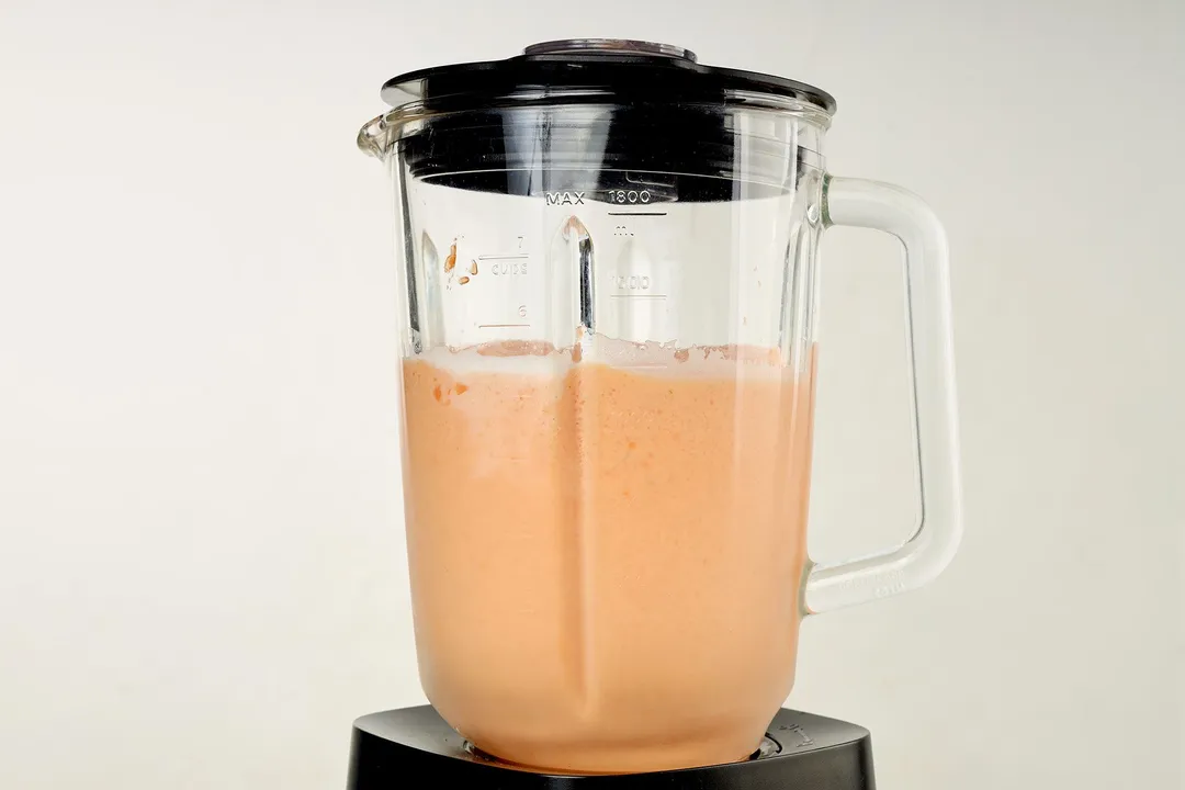 front shot of a blender pitcher with papaya smoothie in it