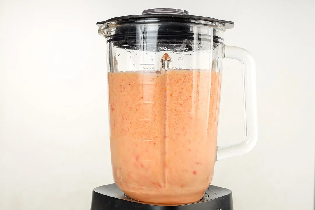 front shot a blender pitcher of pineapple mango strawberry smoothie