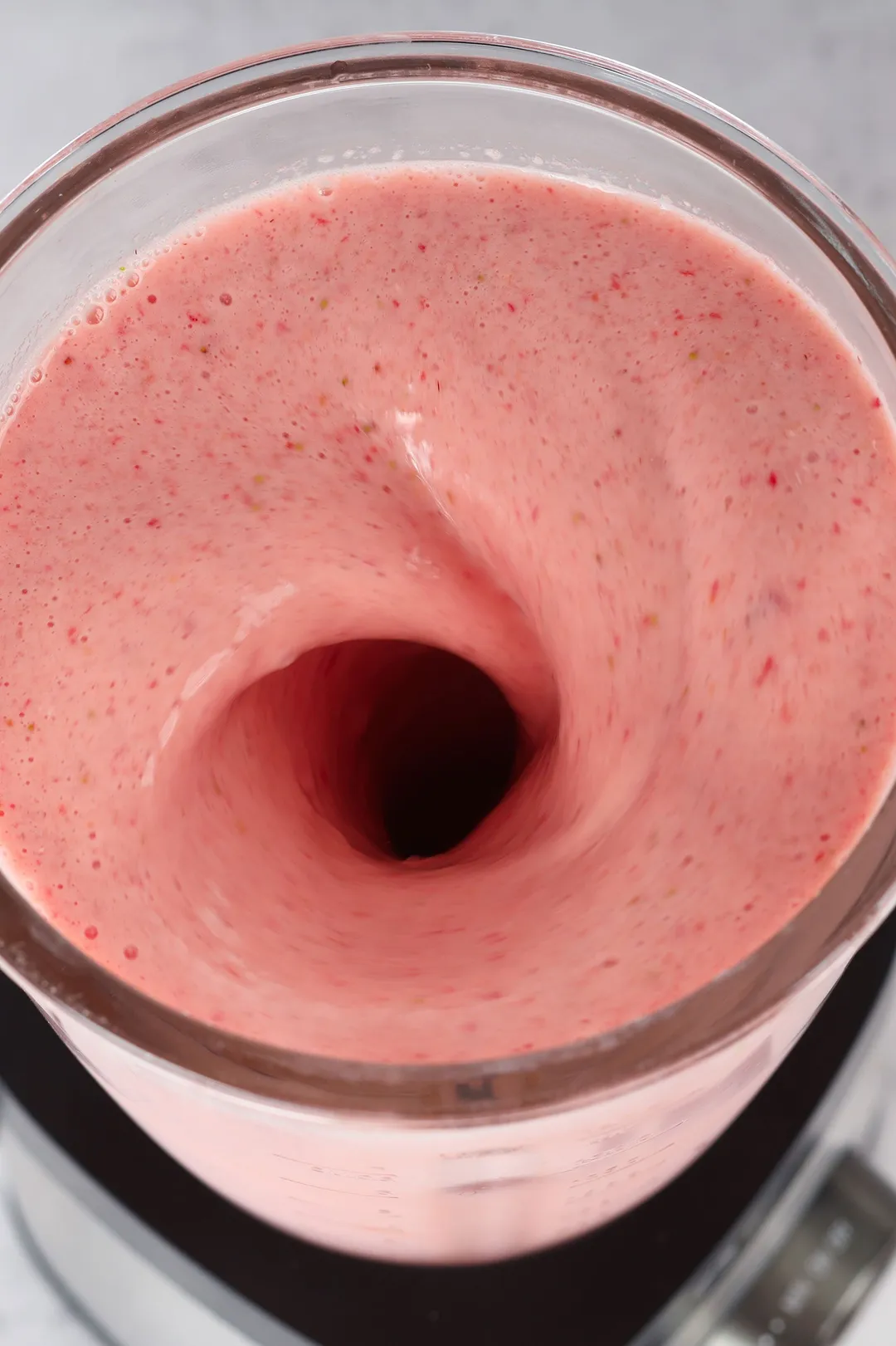 close up shot of a blender blending strawberry orange smoothie