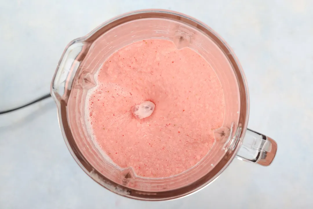 top view of a blender of strawberries pineapple smoothie