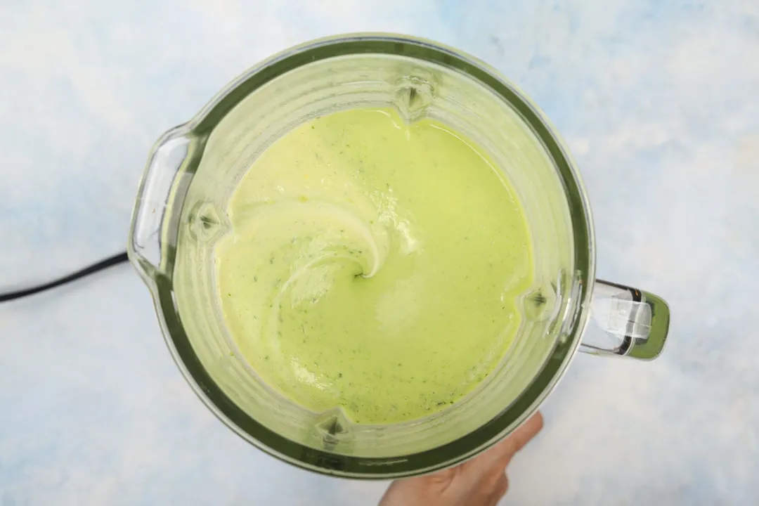 top view of a blender pitcher blending avocado smoothie.