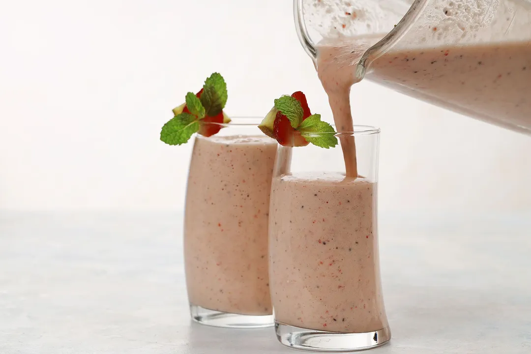 a pitcher pouring smoothie into two glasses