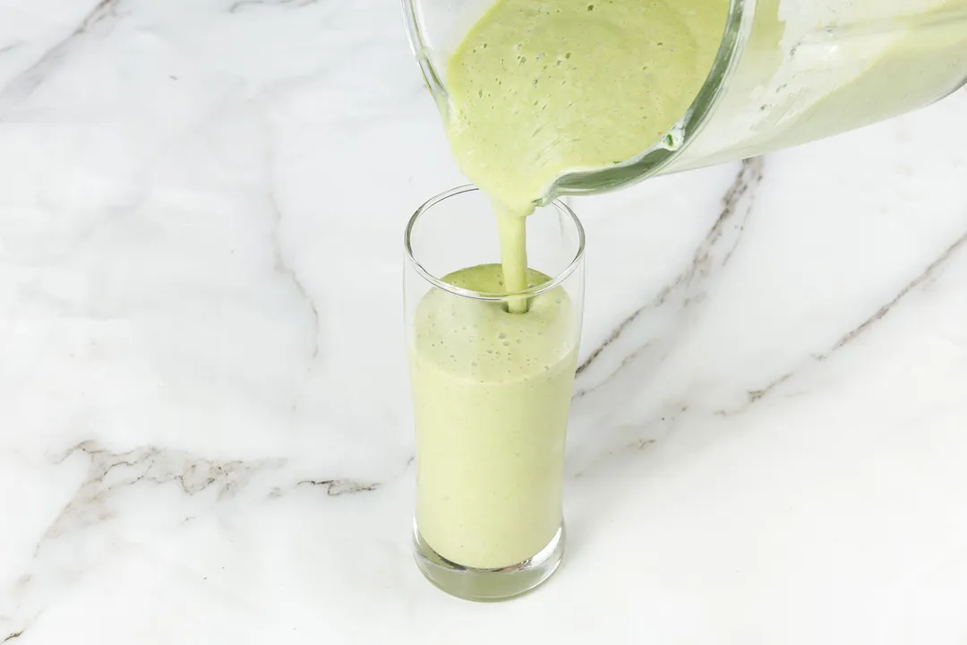 pouring mango smoothie into glass