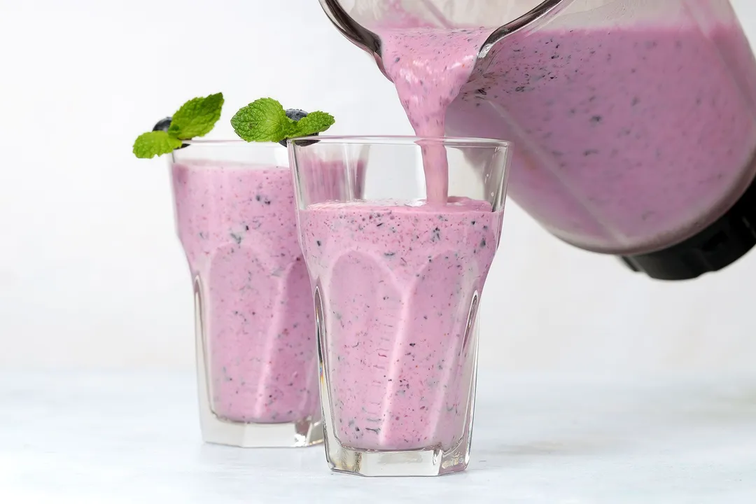 pouring smoothie from a blender pitcher into glasses