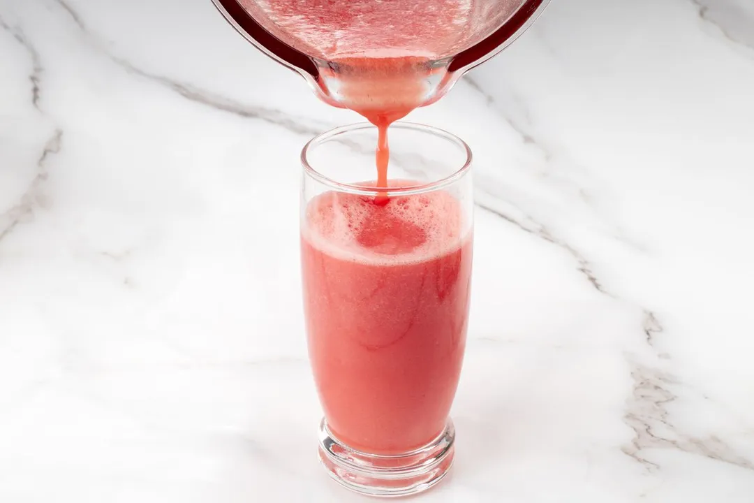 pouring watermelon smoothie from pitcher into glass