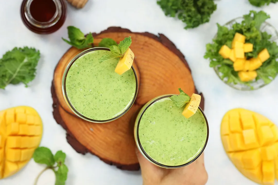 top view of two glass of mango kale smoothie on a tray