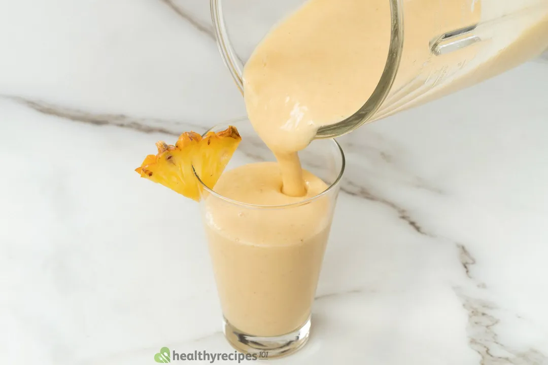 pouring pineapple smoothie from blender pitcher to a glass